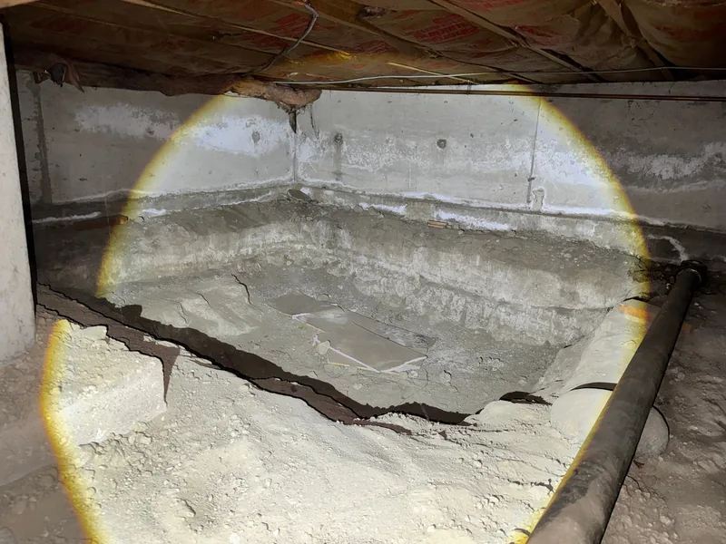 Unfinished crawl space with dirt floor and exposed footing, before mitigation