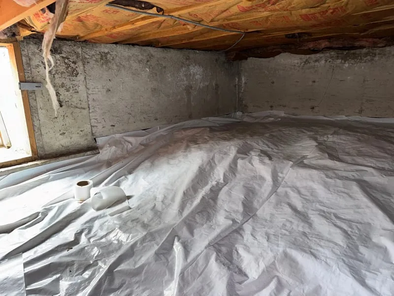 Crawl space floor sealed with a white radon membrane and a suction pipe