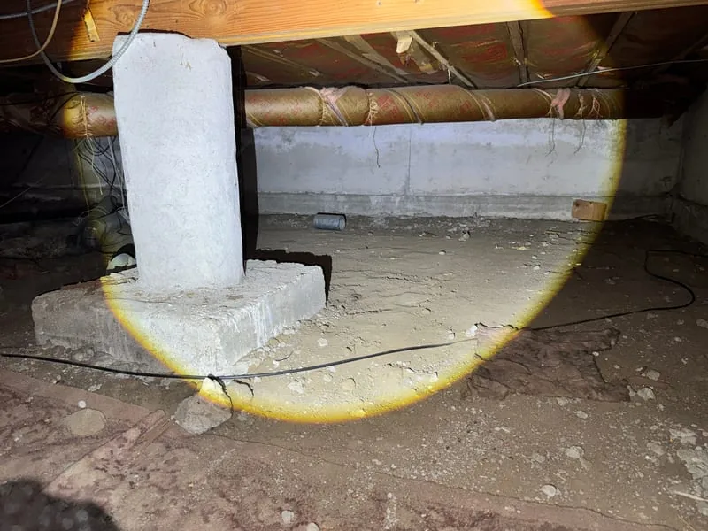 Crawl space with a concrete support pier before the membrane is installed