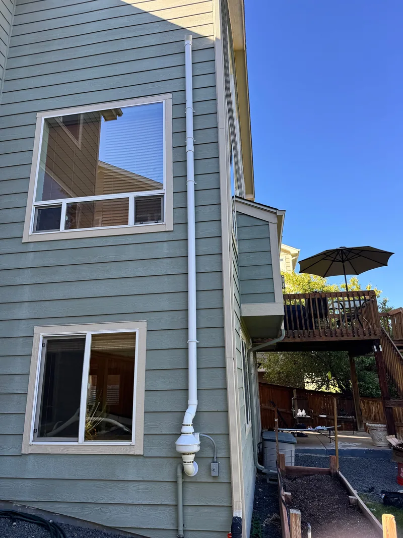 Radon discharge pipe extending above the roofline of a two-story home