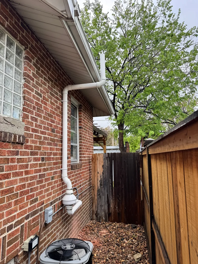 Radon vent pipe on the corner of a red brick ranch home